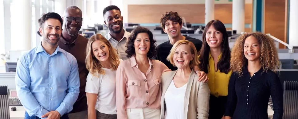 Grupo diverso de personas sonriendo en una oficina.