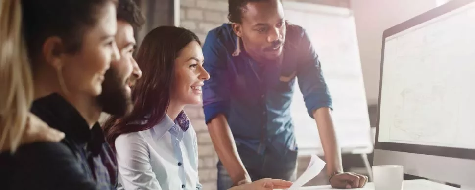 Grupo de personas trabajando juntas frente a una computadora.