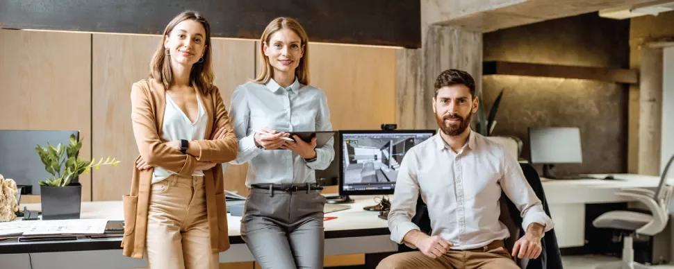 Tres personas en una oficina moderna con computadoras.