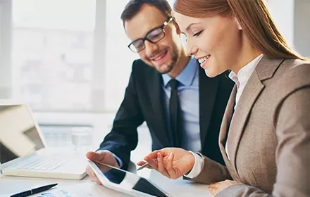 Dos personas revisando información en una tablet en una oficina.