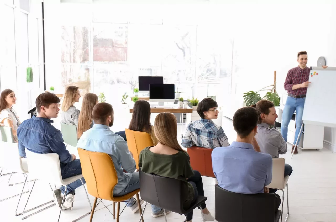 Grupo de personas en una sala de conferencias escuchando una presentación.