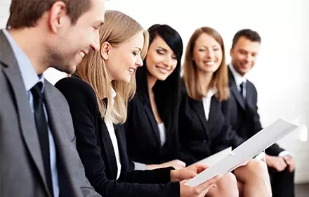 Grupo de personas en trajes formales revisando documentos.
