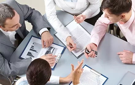 Reunión de trabajo con documentos y gráficos en una mesa.