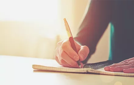 Persona escribiendo en un cuaderno con buena iluminación.