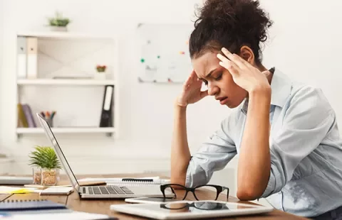 Mujer estresada frente a una computadora en la oficina.
