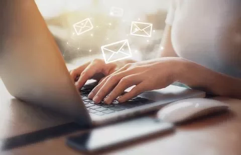 Persona escribiendo en un portátil con iconos de correo.