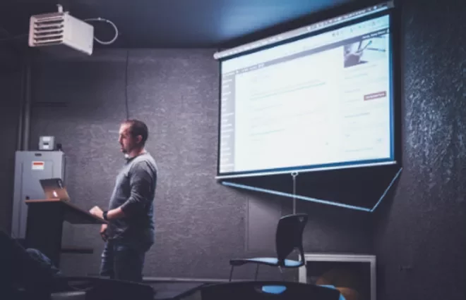 Hombre presentando en una pantalla grande con proyector.