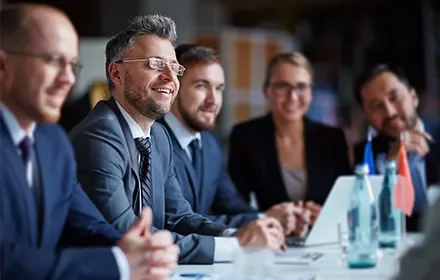 Grupo de personas en una reunión de negocios, sonriendo y conversando.