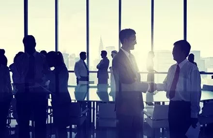 Personas de negocios estrechando manos en una sala de conferencias.
